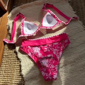 Vista piatta di un bikini rosa a fiori con slip a vita alta e top a fascia imbottito