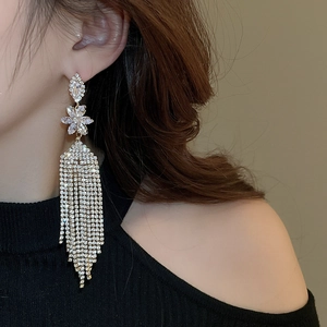 Macro shot of long flower tassel earrings with shimmering crystals on model