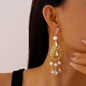 Detail of elegant gold-toned earrings featuring white pearls and crystal drop fringe