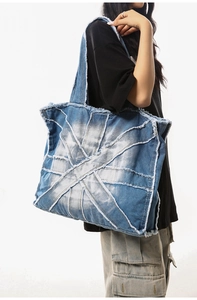Detailed macro view of retro washed blue denim tote bag featuring frayed edge stitching