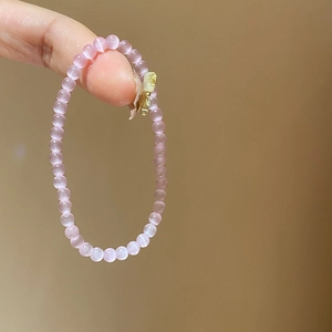 Detail of pink cat-eye stone bead bracelet with a golden butterfly pendant charm