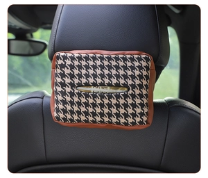 Detail of houndstooth tissue holder hanging on car headrest with brown leather trim