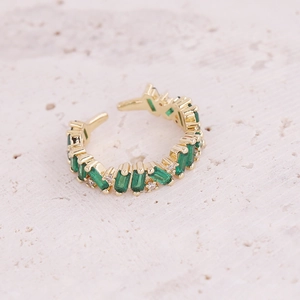Gold open ring with green rectangular zircons and white crystals on stone background