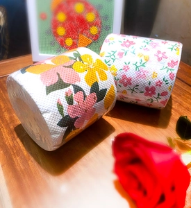 Detail view of two toilet paper rolls with yellow floral and pink碎花 patterns on wood