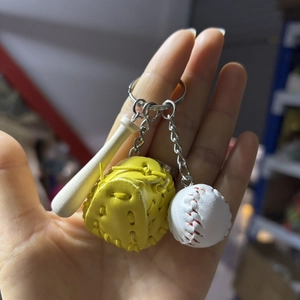 Detailed close-up of a mini baseball set keychain featuring a yellow glove and bat