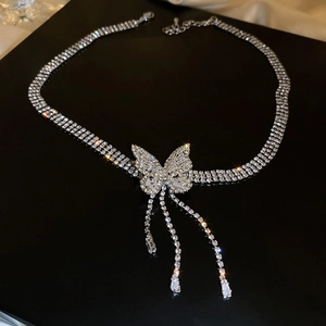 Détail d'un collier papillon argenté avec glands en zircons sur un fond noir élégant
