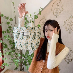 Close-up of elegant daisy embroidery on cream canvas handbag with woven handle