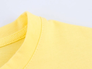 Dettaglio del girocollo e delle cuciture di una maglietta in cotone di colore giallo