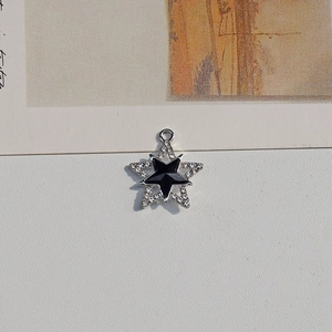 Macro detail of silver star pendant with white rhinestones and black enamel center