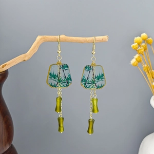 Detail of vintage bamboo tassel earrings with green pendants hanging on a branch