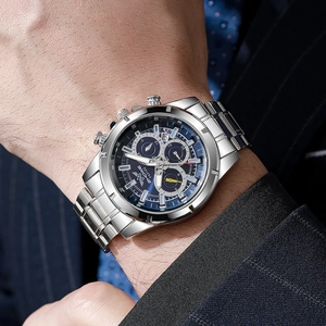 Close-up of men's silver alloy watch with blue dial worn with a navy suit