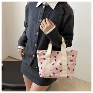 Pink corduroy tote bag with strawberry print and white fabric handles for students