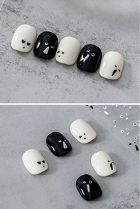 Close-up of minimalist black and white nail stickers with cartoon ghost face designs