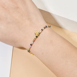 Detail of colorful natural stone beaded bracelet with golden sun-moon pendant on wrist