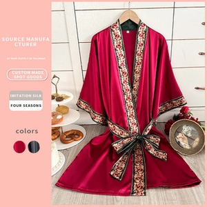 Detail of red imitation silk robe featuring ethnic patterned borders on sleeves and collar