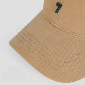 Close-up of khaki cotton baseball cap featuring green number 7 embroidery and neat stitching
