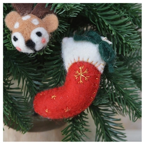 Close-up of wool felt Christmas stocking and reindeer hanging on a pine tree branch