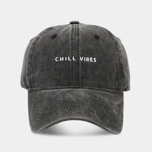 Close-up of Chill Vibes white embroidery on washed dark grey denim baseball cap