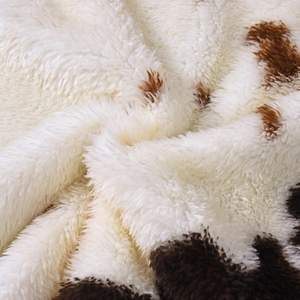 Gros plan détaillé sur un tissu polaire doux avec motif vache marron et texture pelucheuse