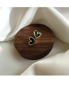 Detail shot of vintage dark green heart earrings with gold trim on silk fabric