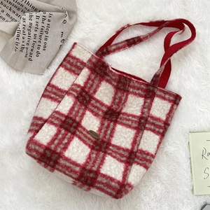 Macro view of red and white checkered lamb wool fabric and metal logo plaque on tote bag