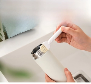 Detail of multi-functional cleaning brush scrubbing the crevices of a thermos lid rim