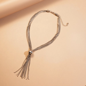 Détail du collier à franges argenté multicouche avec sphère en métal et glands