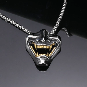 Macro shot of 3D Oni mask pendant with silver finish and gold fangs on box chain