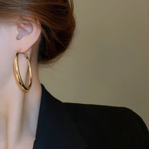 Close-up of chunky gold hoop earrings worn with black formal attire for a modern look