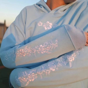 Light blue oversized hoodie featuring white floral embroidery on sleeves and chest
