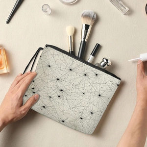 Borsa da trucco in tela con linee radiali nere e cerniera, mostrata con accessori beauty