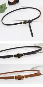 Detail of slim black and brown faux leather belts with golden infinity buckles on a desk