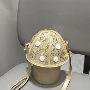 Detail of mushroom shaped shoulder bag with champagne gold rhinestones on a grey chair