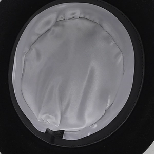 Close-up of the elegant black wool hat featuring a smooth silver satin lining and care label