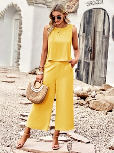 Detail view of yellow sleeveless top and wide-leg trousers on a bright outdoor stone path