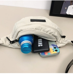 Detail showing high-capacity interior of beige nylon chest bag with phone and water bottle