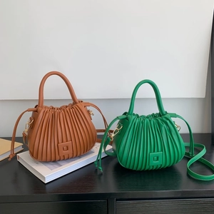 Detail of pleated bucket bags in caramel and green with adjustable leather straps