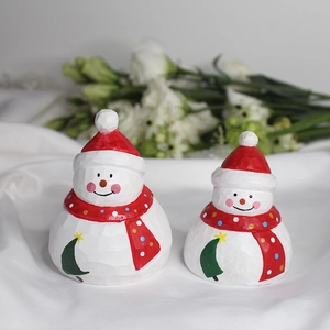 Handcrafted wooden snowman figurines with red knitted hats and green tree patterns