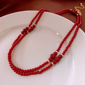 Detail of double-layer red beaded necklace with golden clasps on a ceramic plate