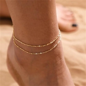 Close-up of minimalist double-layer gold anklet chain on ankle for summer beach wear