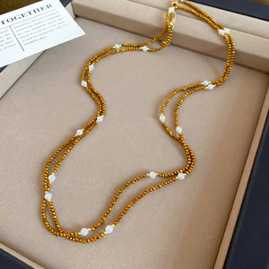 Detail of beaded necklace with gold faceted beads and white pearls on beige velvet