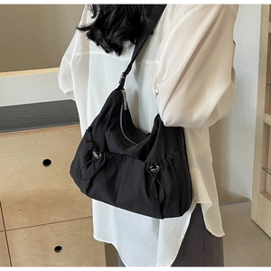 Detail of black nylon pleated shoulder bag showing drawstring toggle and silver zipper