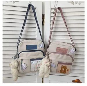 Détail du sac bandoulière en toile avec poche transparente, broderie et peluche lapin