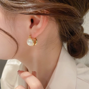 Minimalist gold-plated metal hoop earrings with a single white pearl shown on a model
