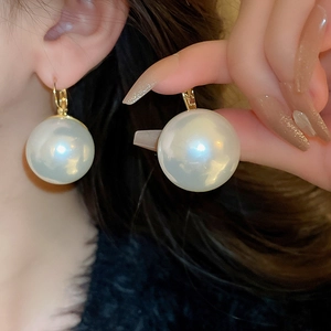 Boucles d'oreilles crochet dorées avec grandes perles rondes blanches sur mannequin