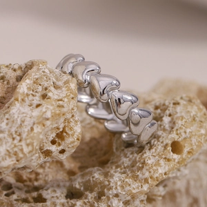 Macro view of silver heart-shaped continuous ring on textured natural stone