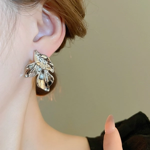 Macro close-up of a silver flower earring featuring artistic pleated metal petal details
