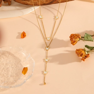 Close-up of a layered gold necklace featuring butterfly pendants with white inlay detail