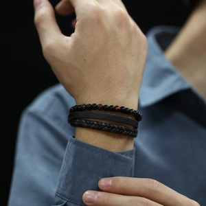 Detail of multi-layer leather bracelet set with red tiger eye beads on male model wrist