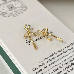 Elegant gold bow stud earrings in 925 sterling silver on a minimalist gift box display